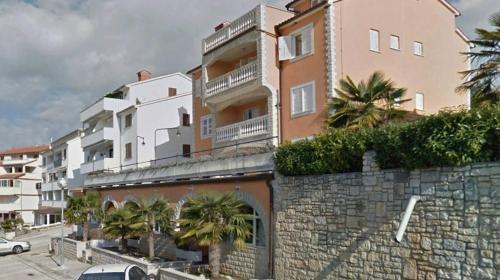 a building with palm trees on the side of it at Sunny Adriatic apartments Valentin in Vrsar