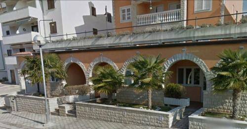 a building with palm trees in front of it at Sunny Adriatic apartments Valentin in Vrsar