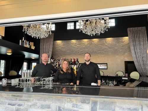 a group of three people standing at a bar at Inn of Chagrin in Chagrin Falls