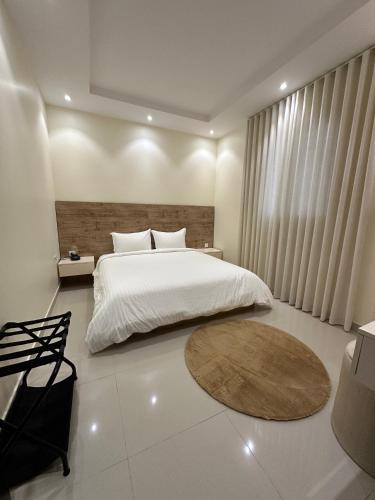 a bedroom with a white bed and a wooden headboard at Zaan Apartment Al-Nafel in Riyadh