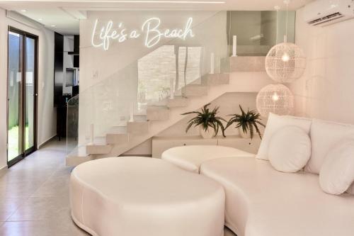 Hospedagem Triplex Vista Beira Mar 7 Estrelas Patacho في بورتو دي بيدراس: غرفة معيشة مع أريكة بيضاء والدرج