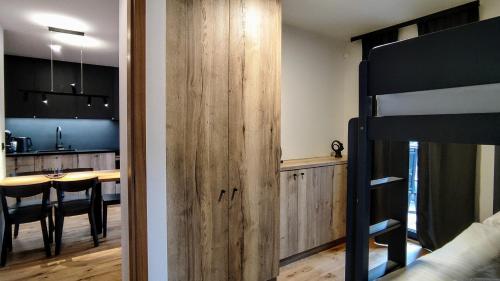 a room with a bunk bed and a kitchen with a table at Moderní rodinný 3KK apartmán D8 v centru Harrachova s výhledem na skokanské můstky - by Relax Harrachov in Harrachov