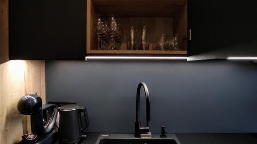 a kitchen with a sink and a counter with glasses at Moderní rodinný 3KK apartmán D8 v centru Harrachova s výhledem na skokanské můstky - by Relax Harrachov in Harrachov