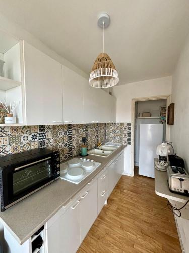 une cuisine avec des armoires blanches et un micro-ondes dans l'établissement Appartement au pied de la Dune et Parking privé, à Berck-sur-Mer