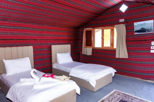 2 letti in una camera con parete rossa di Wadi Rum Sights Camp a Wadi Rum