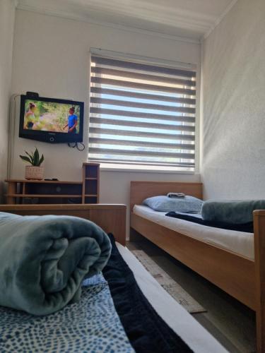 a bedroom with two beds and a flat screen tv at Visit Drežnica in Mostar