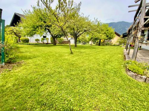 een tuin met groen gras en bomen en een huis bij GARDEN PARADISE - Ferienhaus mit 400m2 Garten - Nähe Ossiacher See in Villach