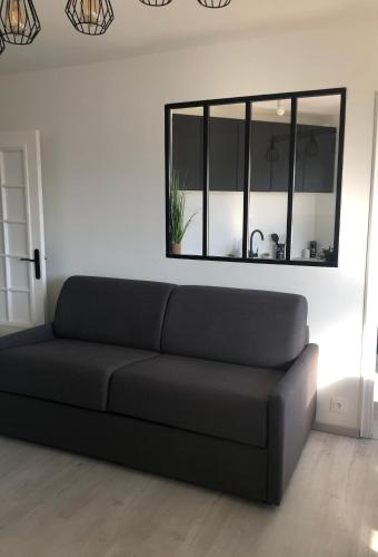 - un canapé noir dans le salon avec un miroir dans l'établissement T1 panoramique, à Mandelieu-la-Napoule