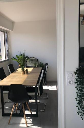 une salle à manger avec une table en bois et des chaises noires dans l'établissement T1 panoramique, à Mandelieu-la-Napoule