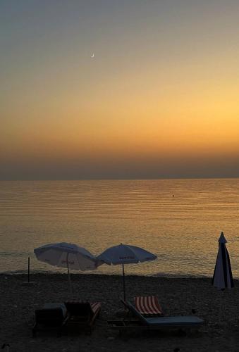 two umbrellas and chairs on a beach with the ocean at Sunflower Himara in Himare