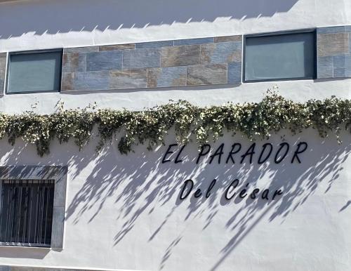 a sign on the side of a building with plants at El Parador del César in Merida