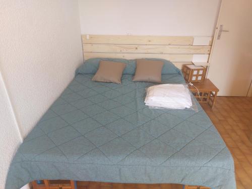 uma cama com um edredão azul e duas almofadas em Dernier étage vue mer exceptionnelle em Roquebrune-Cap-Martin