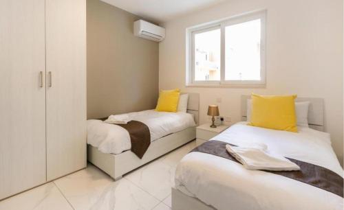 two beds in a bedroom with yellow and white at Emerald Suite in St Paul's Bay