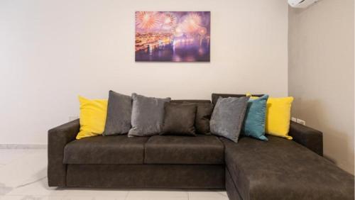 a brown couch with colorful pillows in a living room at Emerald Suite in St Paul's Bay