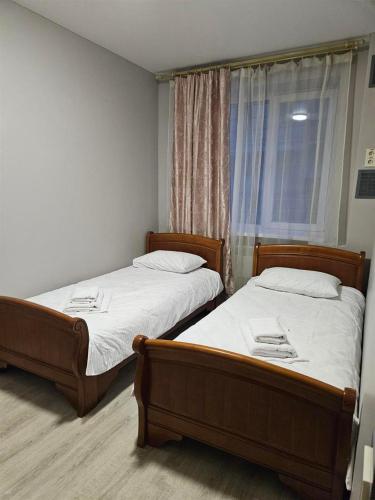 2 Einzelbetten in einem Zimmer mit Fenster in der Unterkunft Біля Замку in Lwiw