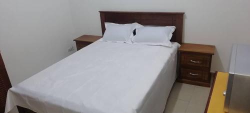 un grand lit blanc avec deux oreillers dessus dans l'établissement AMDI Appartement, à Dakar