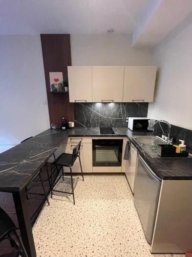 une cuisine avec un comptoir noir et des armoires blanches dans l'établissement Appartement au cœur du centre ville de Carcassonne, à Carcassonne