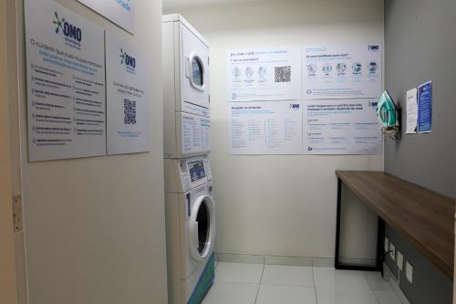 a laundry room with a washing machine and posters on the wall at Intercity São Paulo Ibirapuera in Sao Paulo