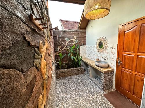 a bathroom with a stone wall and a wooden door at Sunny Rose Bungalows Gili Air - Adults only in Gili Air