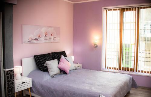 1 dormitorio con paredes moradas y 1 cama con almohadas en Studio Violet, en Burgas