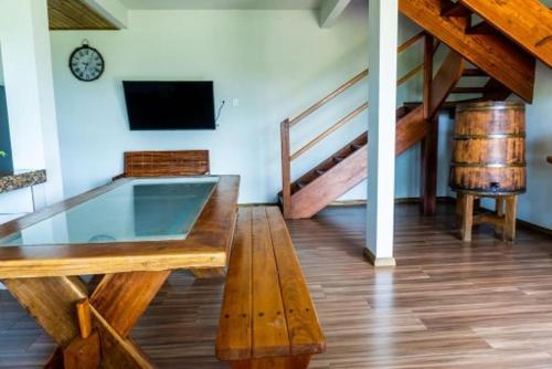 a room with a wooden table and a tv and stairs at Casa Mar - Taipu de Fora - Maraú - Grupo Barril in Marau