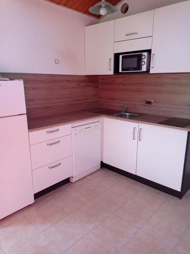 une cuisine avec des armoires blanches et un micro-ondes dans l'établissement Victoria 204, à Saint-Jean-de-Monts