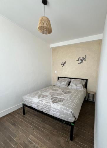 - une chambre avec un lit et une lampe pendant dans l'établissement TY GWEN Appart1, à Châteaulin