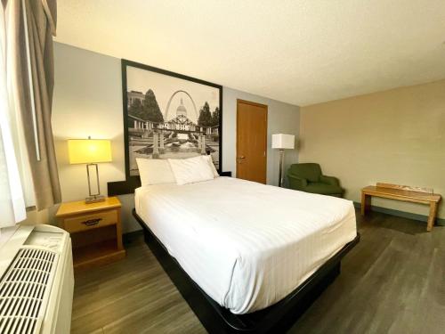 una camera d'albergo con un grande letto e una sedia di Super 8 by Wyndham St. Clair MO a Saint Clair