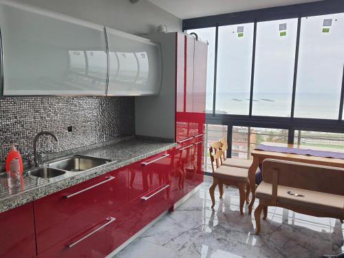 een keuken met rode kasten en een tafel en ramen bij North Star Apart Trabzon in Yomra
