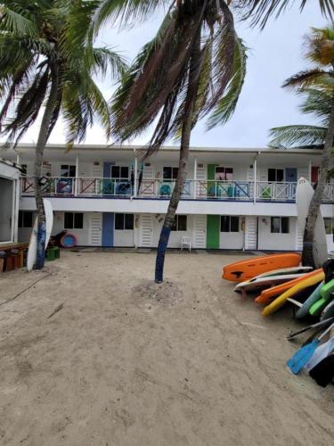 Buenavista的住宿－Mangrove Bay Hotel，海滩上一座棕榈树和冲浪板的建筑