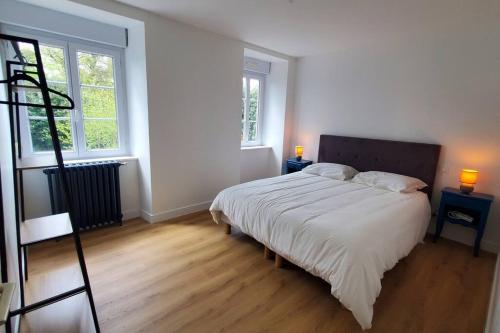 une chambre avec un grand lit et deux fenêtres dans l'établissement Le Couvent B, à Saint-Jean-Kerdaniel