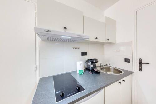 une cuisine avec des armoires blanches et un évier dans l'établissement Studio douillet, à Sarcelles