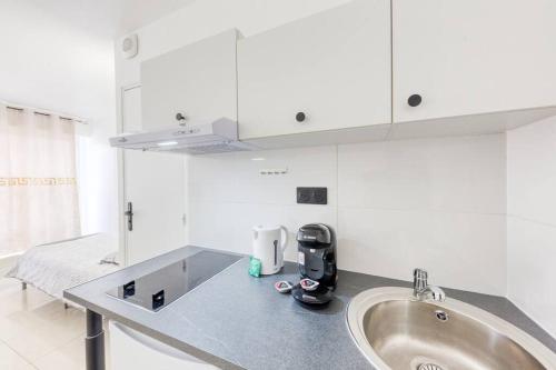d'un comptoir de cuisine avec un évier et des placards blancs. dans l'établissement Studio douillet, à Sarcelles