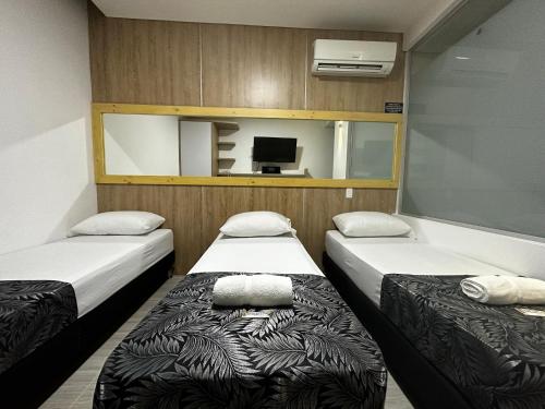 two beds in a small room with a tv at HOTEL PISO 12 in Bello