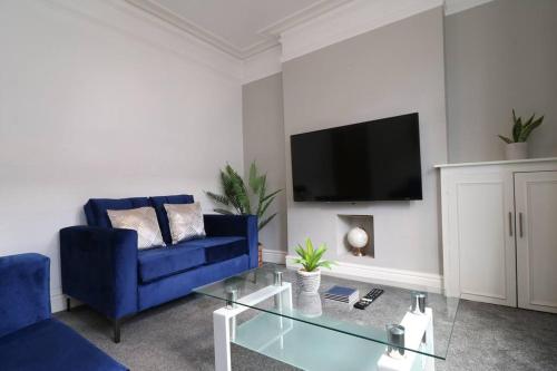 uma sala de estar com um sofá azul e uma televisão em 2 Bedroom Characterful House em Lancaster