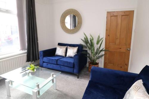 uma sala de estar com um sofá azul e uma mesa em 2 Bedroom Characterful House em Lancaster