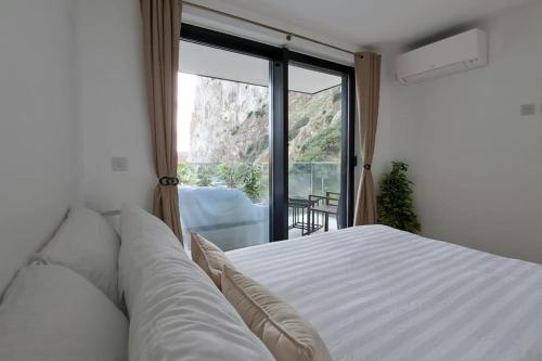 1 dormitorio con cama blanca y ventana grande en 2BR apartment with Spa & Gym en Gibraltar
