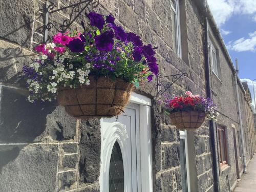 dos cestas de flores a un lado de un edificio en The Garden Flat, en Crieff