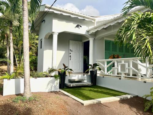 a white house with a porch and palm trees at Villa Lu-Ja in Mount Cassell Land Settlement