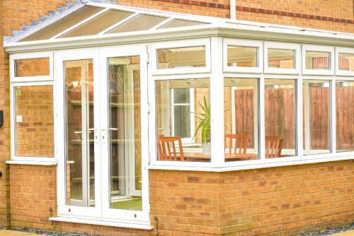 a conservatory with white doors on a brick house at Rider Gardens Holiday House in Boston