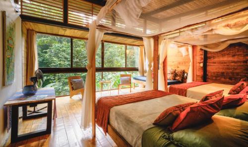 a bedroom with two beds and a large window at La Shamana - Ecological Concept in Jungle in Cahuita