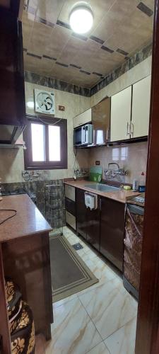a kitchen with brown cabinets and a counter top at شقة دوبلكس مكيفة مفروشة بالكامل فرش جديد بالمنصورة in Mansoura