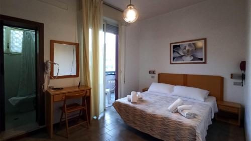 a bedroom with a bed and a bathroom with a mirror at Hotel La Caravella in Bellaria-Igea Marina