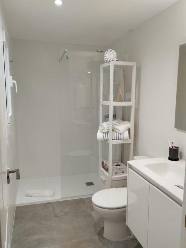 a white bathroom with a toilet and a sink at Apartamento Terraza Mar El Azul in Santa Susanna