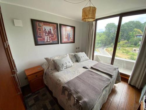 a bedroom with a bed and a large window at Dpto Pucon - Pinares 2D 2B in Pucón