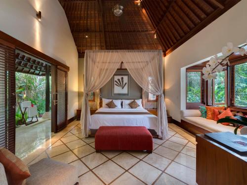 a bedroom with a large bed in a room with windows at Villa Asta in Seminyak