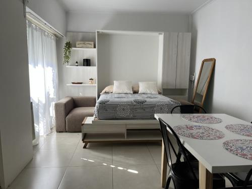 1 dormitorio con 1 cama, mesa y sillas en Destino Guemes Hola Sur en Mar del Plata