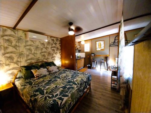 a bedroom with a bed and a room with a kitchen at MOOREA - Tropical Nest in Hauru
