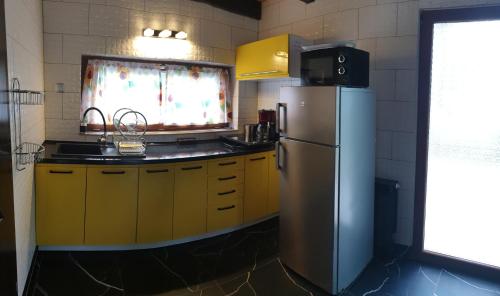 a kitchen with yellow cabinets and a refrigerator at Apartament Aurelia in Świnoujście