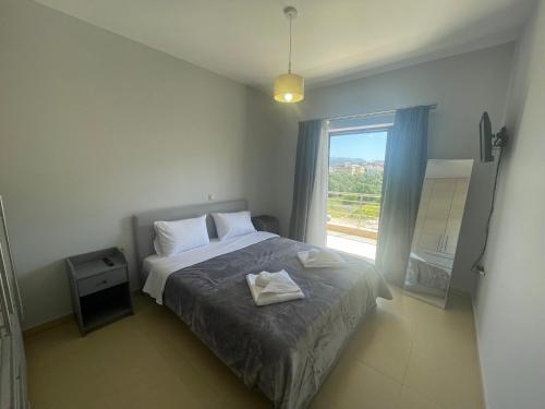 ein Schlafzimmer mit einem Bett und einem großen Fenster in der Unterkunft Villa Melydron in Nafplio